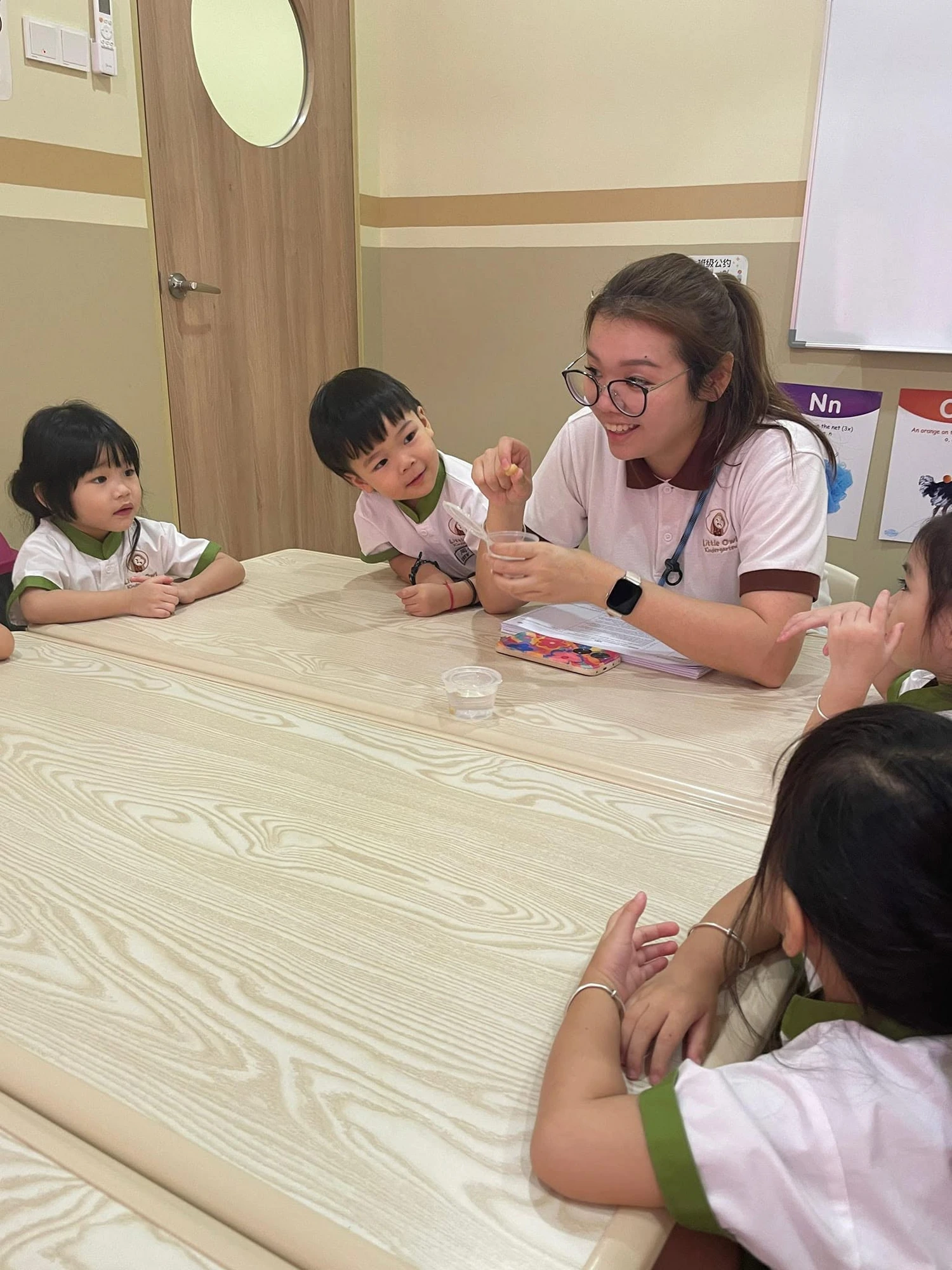 A Little Owl teacher guiding children in the classroom