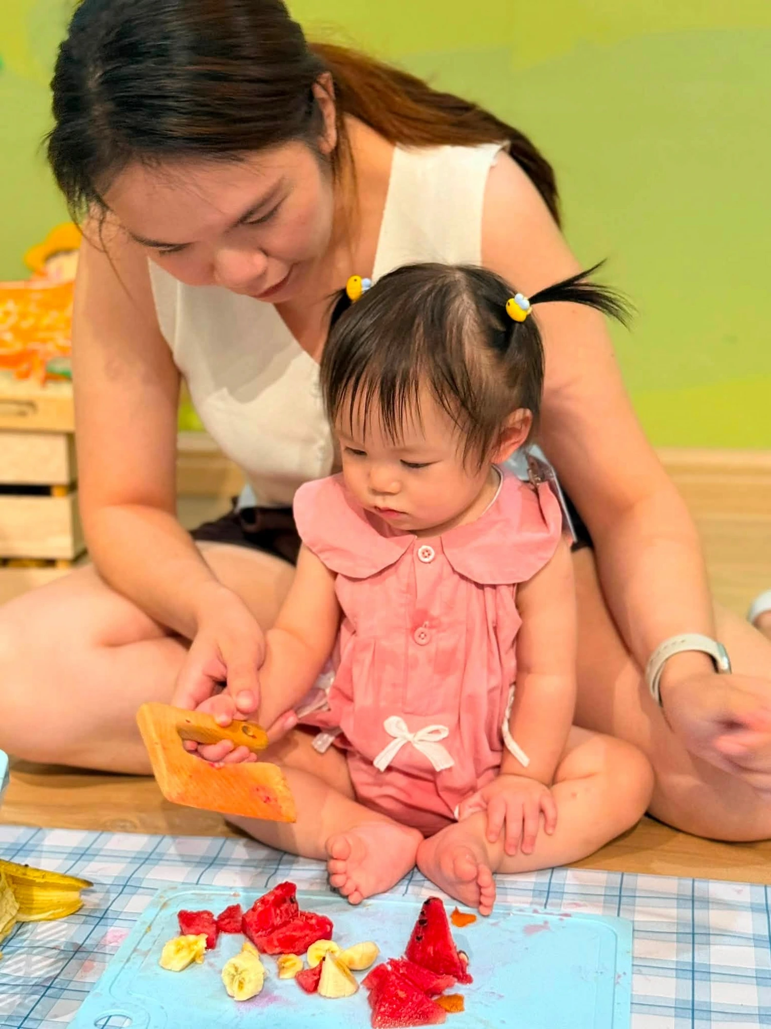 Little Owl teacher and toddler exploring fruit during a Messy Play session